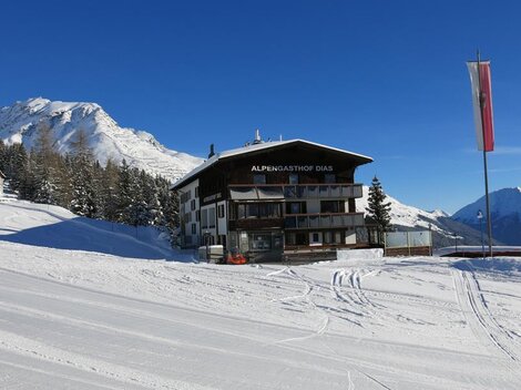 Ein schönes Chalet in einer verschneiten Berglandschaft. Klare blaue Himmel und umgebende Nadelbäume.