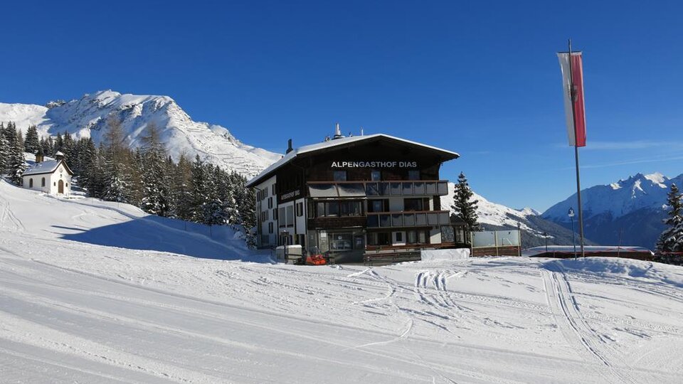Ein schönes Chalet in einer verschneiten Berglandschaft. Klare blaue Himmel und umgebende Nadelbäume.