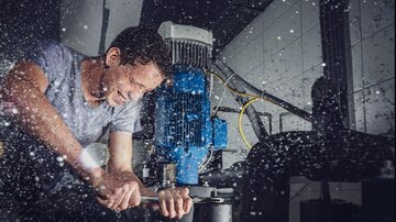 Ein Mann arbeitet an einer Maschine und ist von Wasser umgeben. Er scheint konzentriert und engagiert bei seiner Tätigkeit.