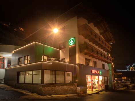 Ein Geschäft mit hellem Licht bei Nacht. Es ist ein SPAR-Markt in einem modernen Gebäude.